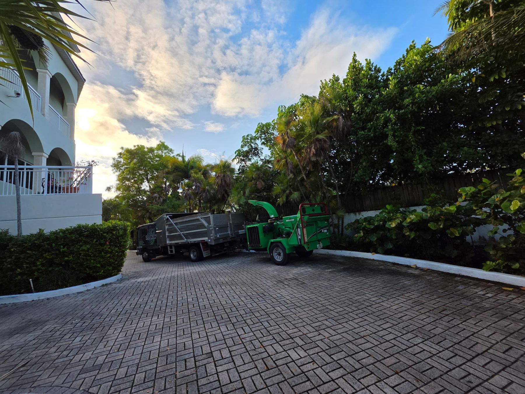 Dump truck and chipper on a clean paver driveway after a job