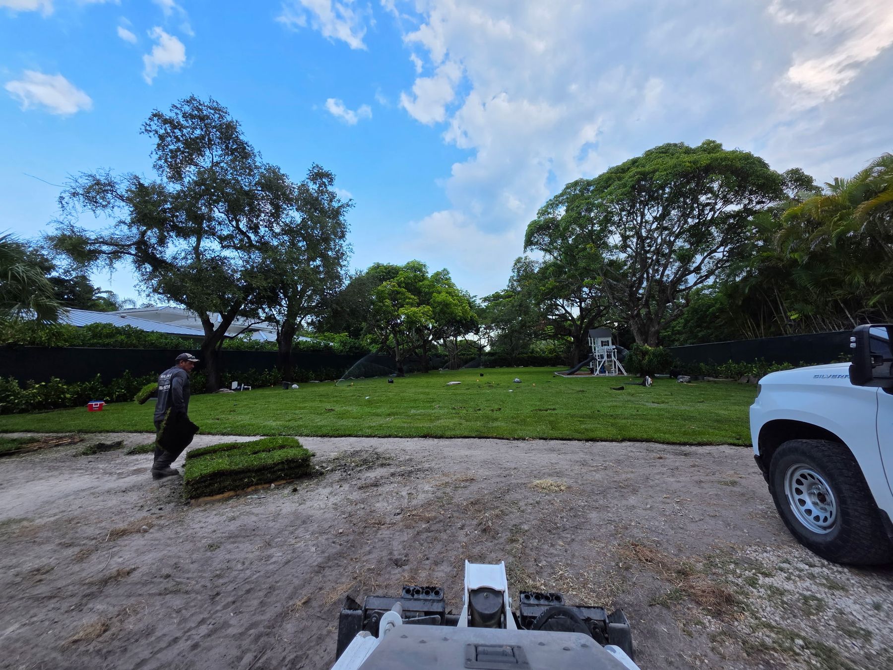 Crew member laying fresh sod across a big backyard